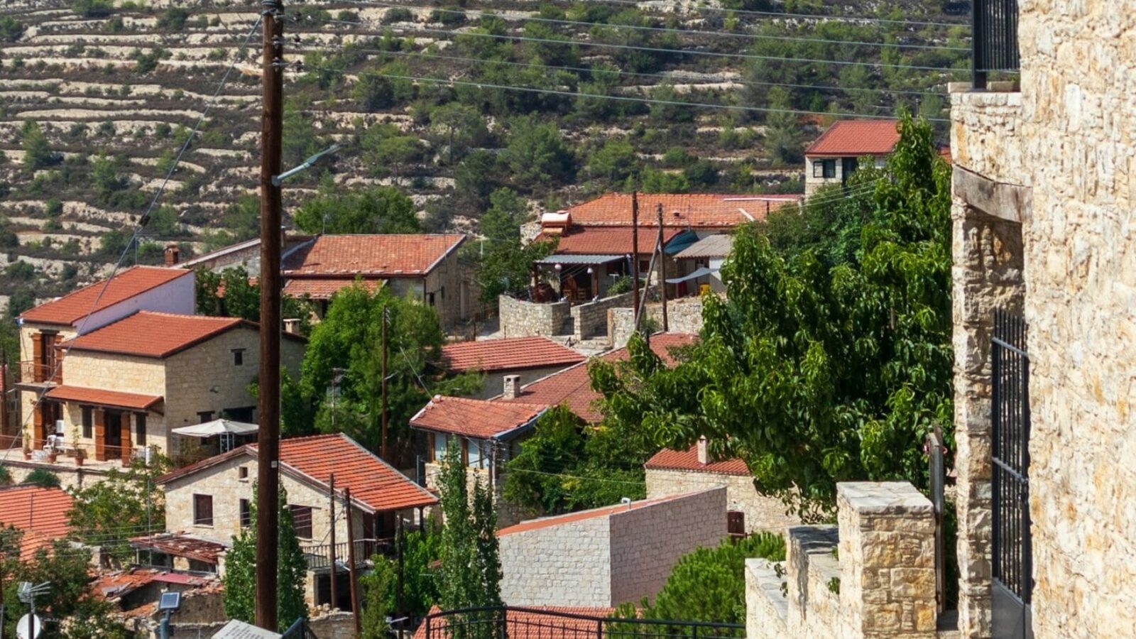 A Troodos mountain village of stone houses with red-tiled roofs, terraced hillsides behind