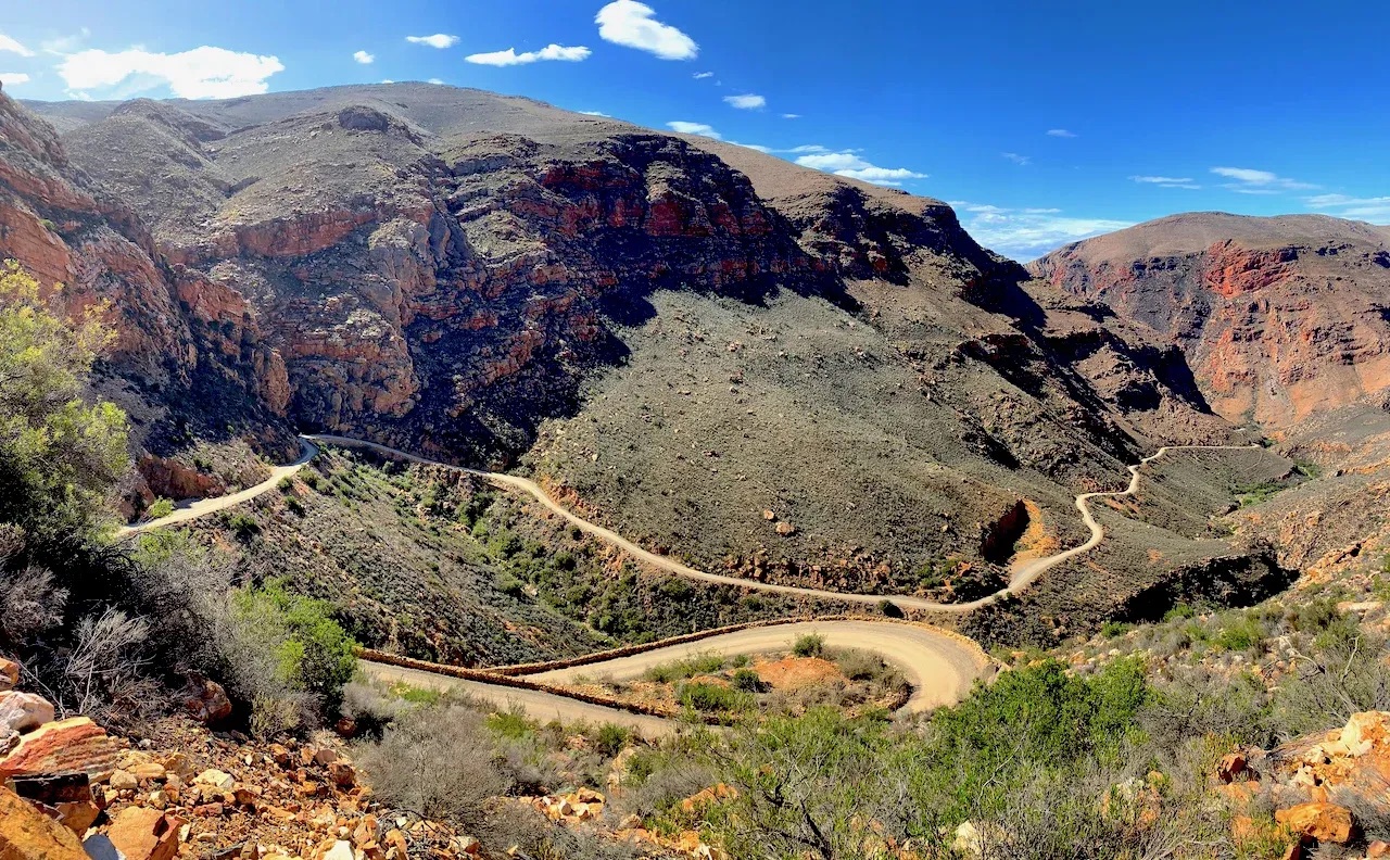 Hairpins of a gravel pass cut into red rock in the Western Cape