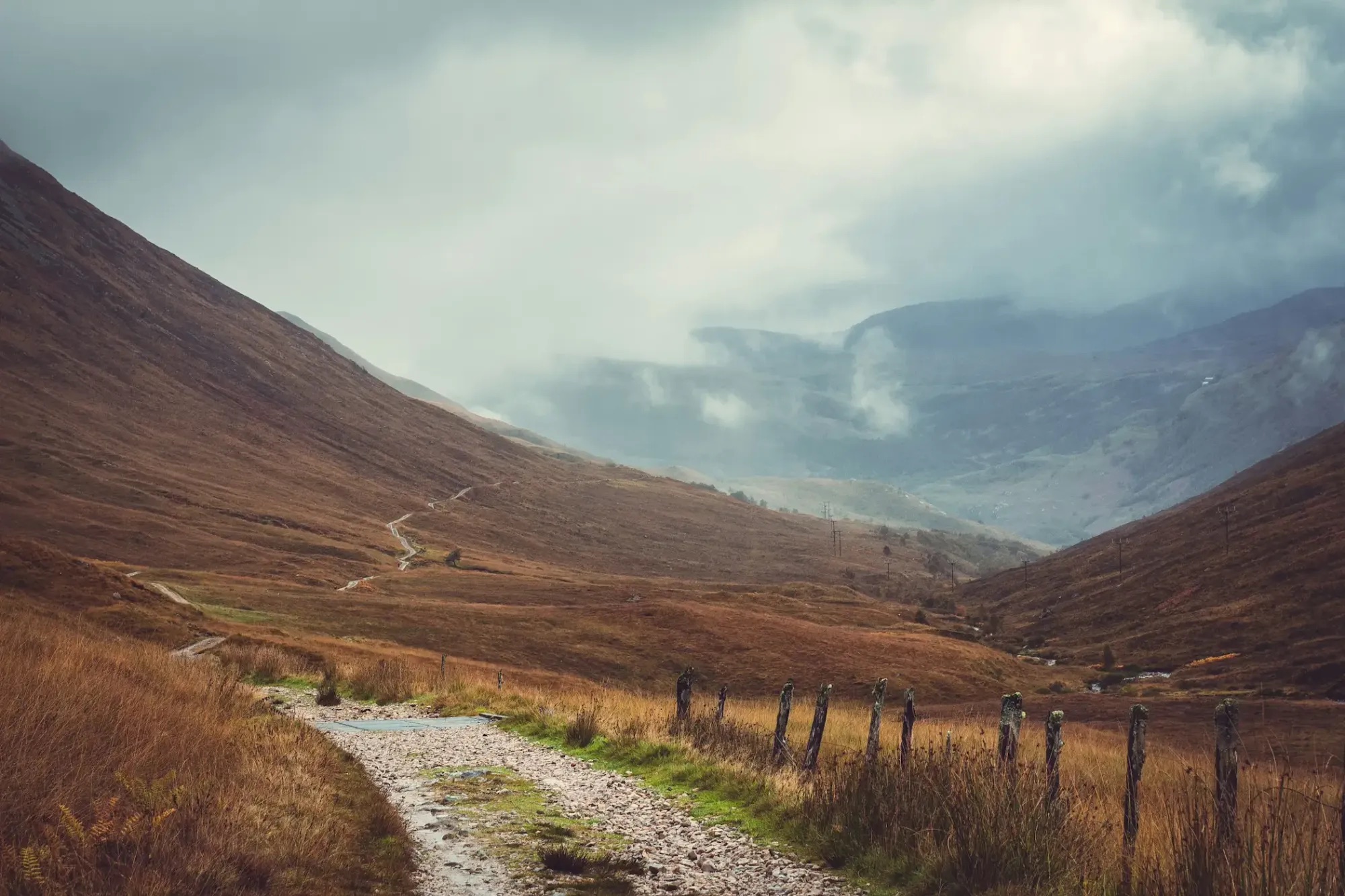 A stony track running up an empty Highland glen under low cloud