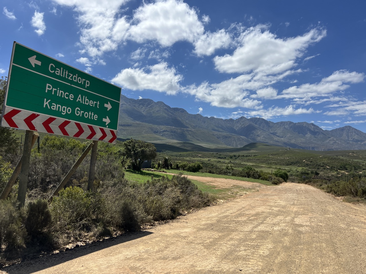 A road sign pointing to Calitzdorp, Prince Albert and the Kango Caves, with the Swartberg mountains behind
