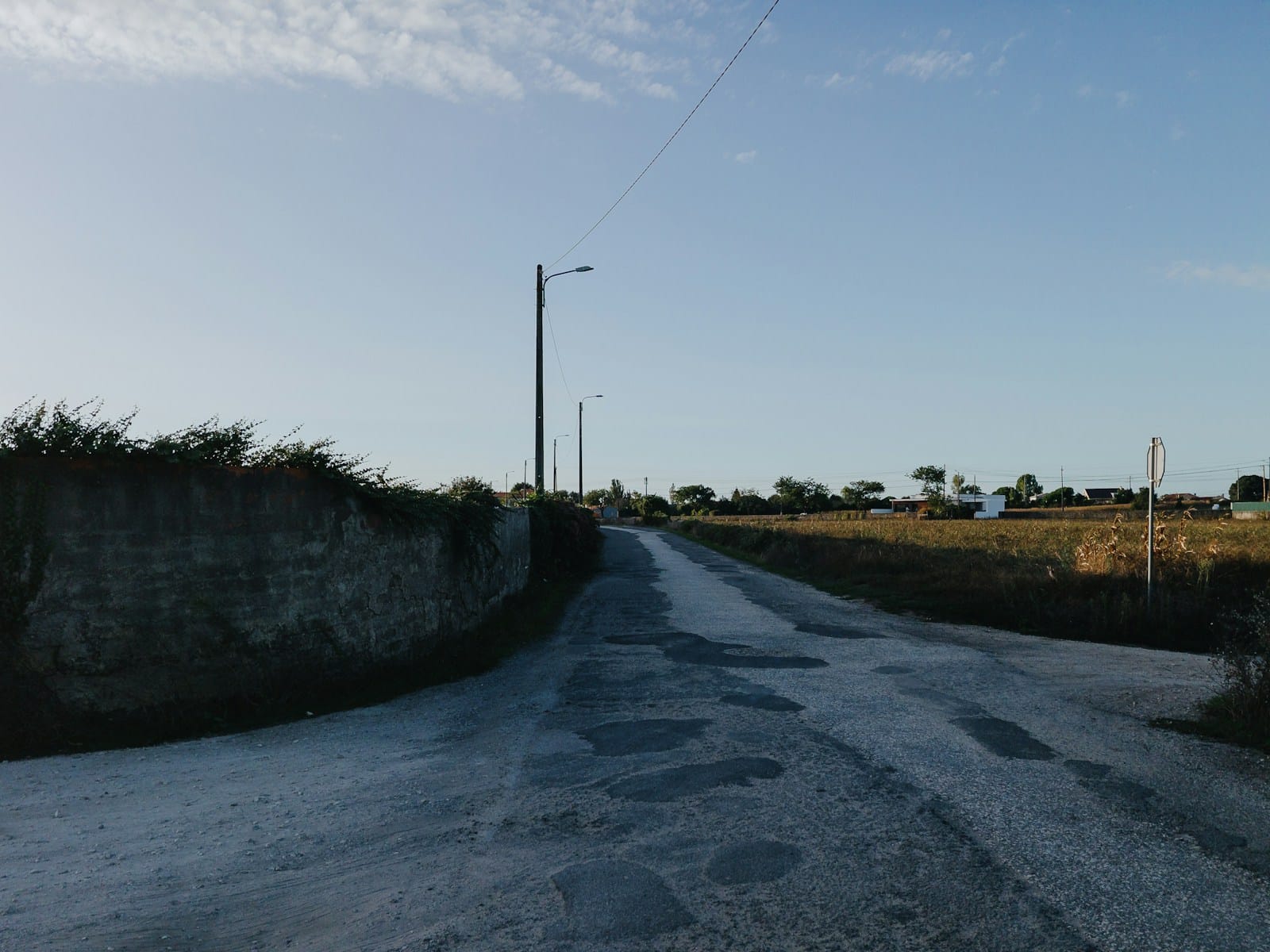 A quiet rural lane running out of a village in low evening light